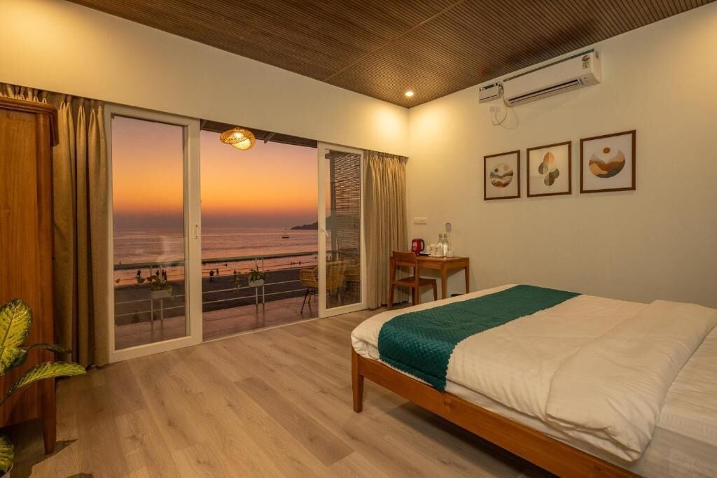 Une chambre d’hôtel équipée d’un lit, d’un bureau, d’une chaise, offrant une vue sur la mer et dotée d’un ventilateur de plafond.