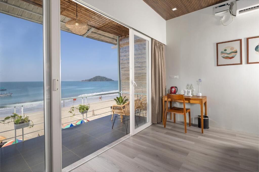 Ein Zimmer mit einer großen Schiebeglasdoor zum Balkon mit Blick auf Strand und Meer.