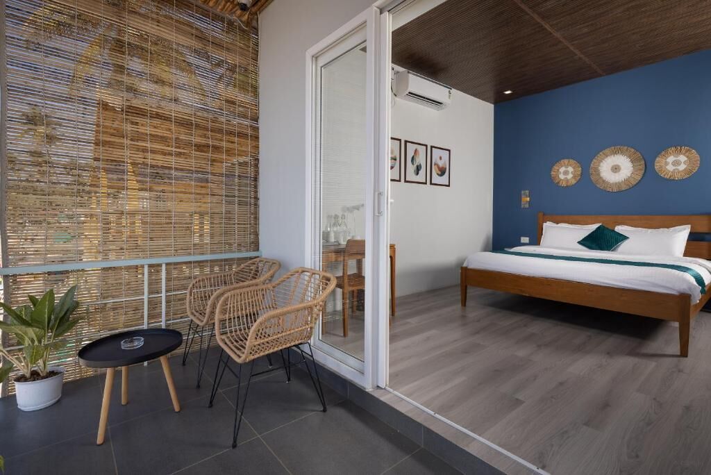 A room with a bed, a small table, two chairs, and a potted plant.
