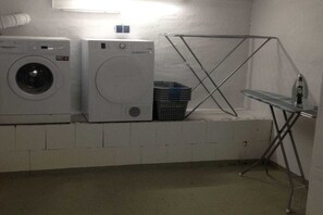 A laundry area with two washing machines, a drying rack, and a stack of laundry baskets. - smuckes to Huus||Bünsdorf (Bünsdorf)