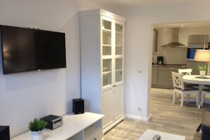 A modern living room with a flat-screen TV, a white cabinet, and a dining area with a table and chairs. - smuckes to Huus||Bünsdorf (Bünsdorf)