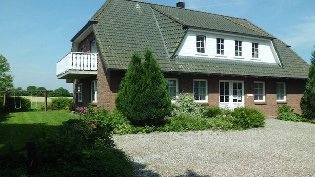 A two-story house with a balcony, a gravel driveway, and a well-maintained garden. - Eckeberg with balcony (Hasselberg)