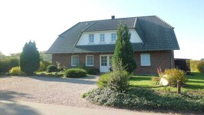 A two-story house with a sloped roof, a front porch, and a gravel driveway. - Eckeberg with balcony (Hasselberg)