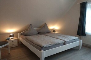 Ein Schlafzimmer mit einem Bett, Nachttischen, Lampen und einem Fenster mit Vorhängen.