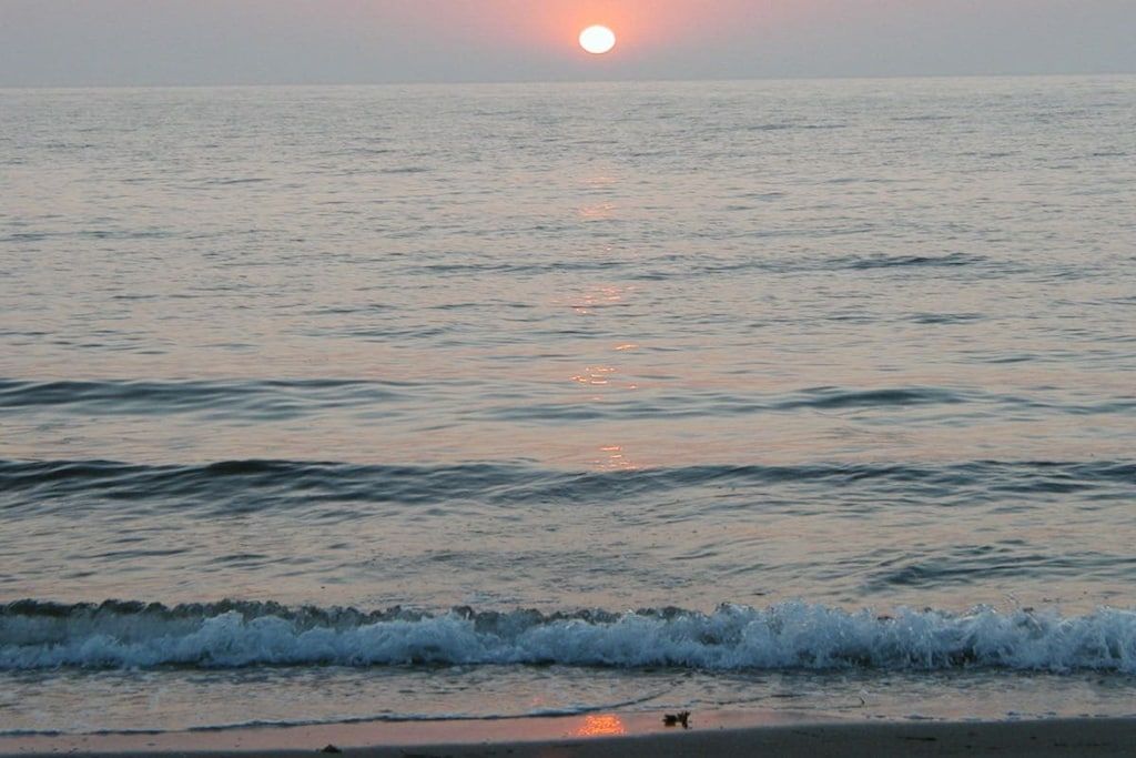 Una playa con olas y un atardecer.