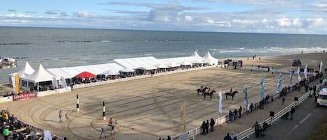 Una pista de carreras de caballos frente al mar, con carpas y espectadores.