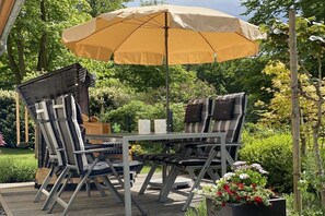 An outdoor patio with a table and chairs, an umbrella, and potted plants. - Holiday apartment with 2 bedrooms (Sellin)