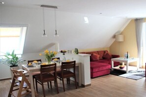 A modern living space with a dining area, a red sofa, and a small white table. - Holiday apartment with 2 bedrooms (Sellin)