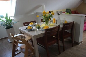 Een eethoek met een witte tafel gedekt voor vier personen, omringd door houten stoelen.