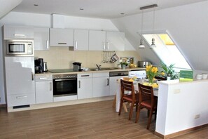 A modern kitchen with white cabinetry, a built-in oven, and a dining area with a table and chairs. - Holiday apartment with 2 bedrooms (Sellin)