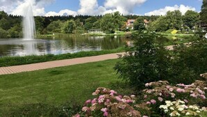 Een park met een fontein, een wandelpad en een vijver.