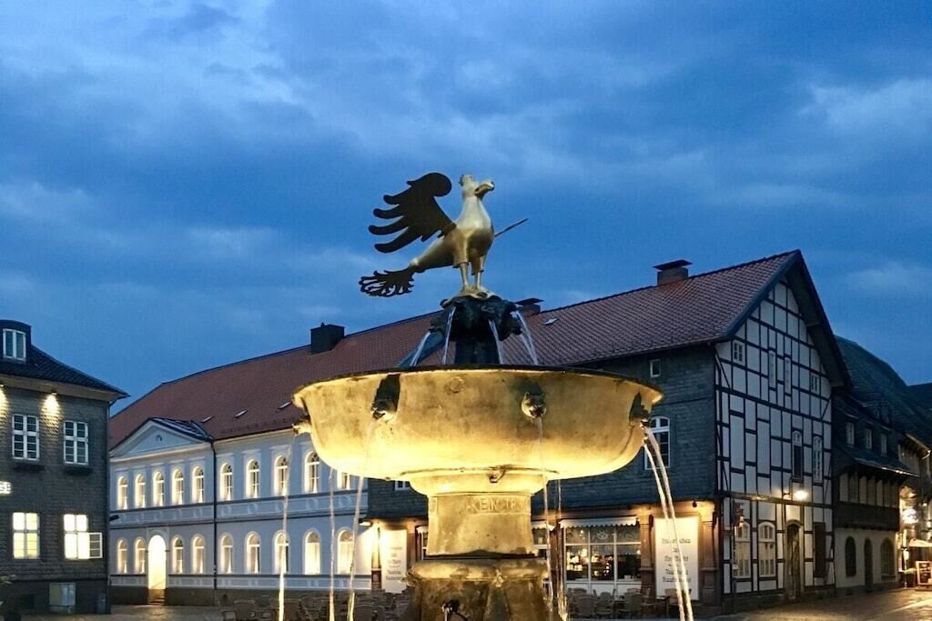 Un bâtiment historique doté d’une fontaine ornée d’une statue de coq.