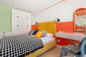 Ein modernes Schlafzimmer mit Bett, Nachttisch, Sessel und Spiegel.