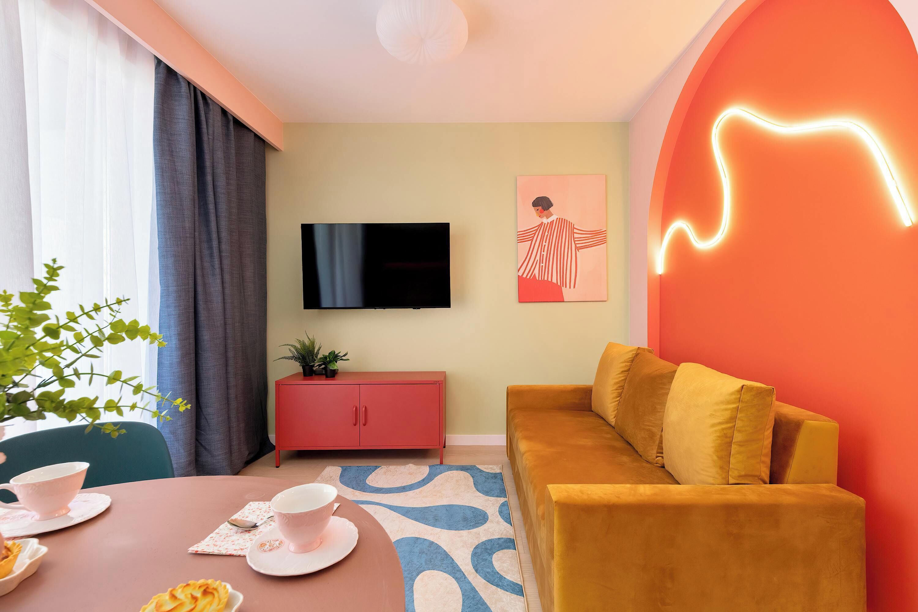 A cozy living room with a mustard sofa, armchair, coffee table, and colorful decor.