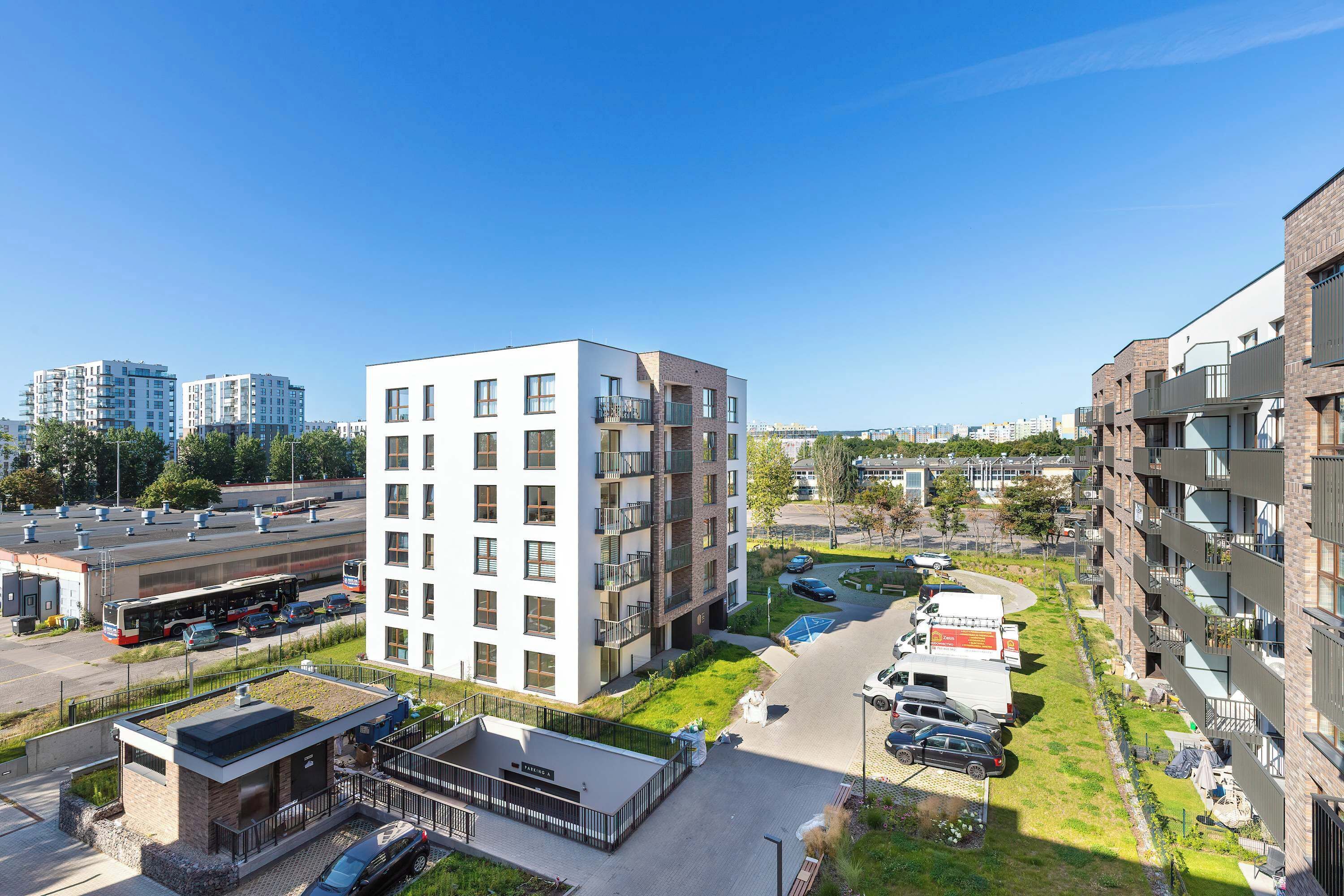 A modern apartment building with multiple floors, a rooftop garden, and a parking area.