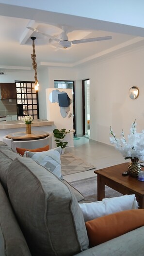 Uma sala de estar moderna com um sofá, uma mesa de centro e um ventilador de teto.