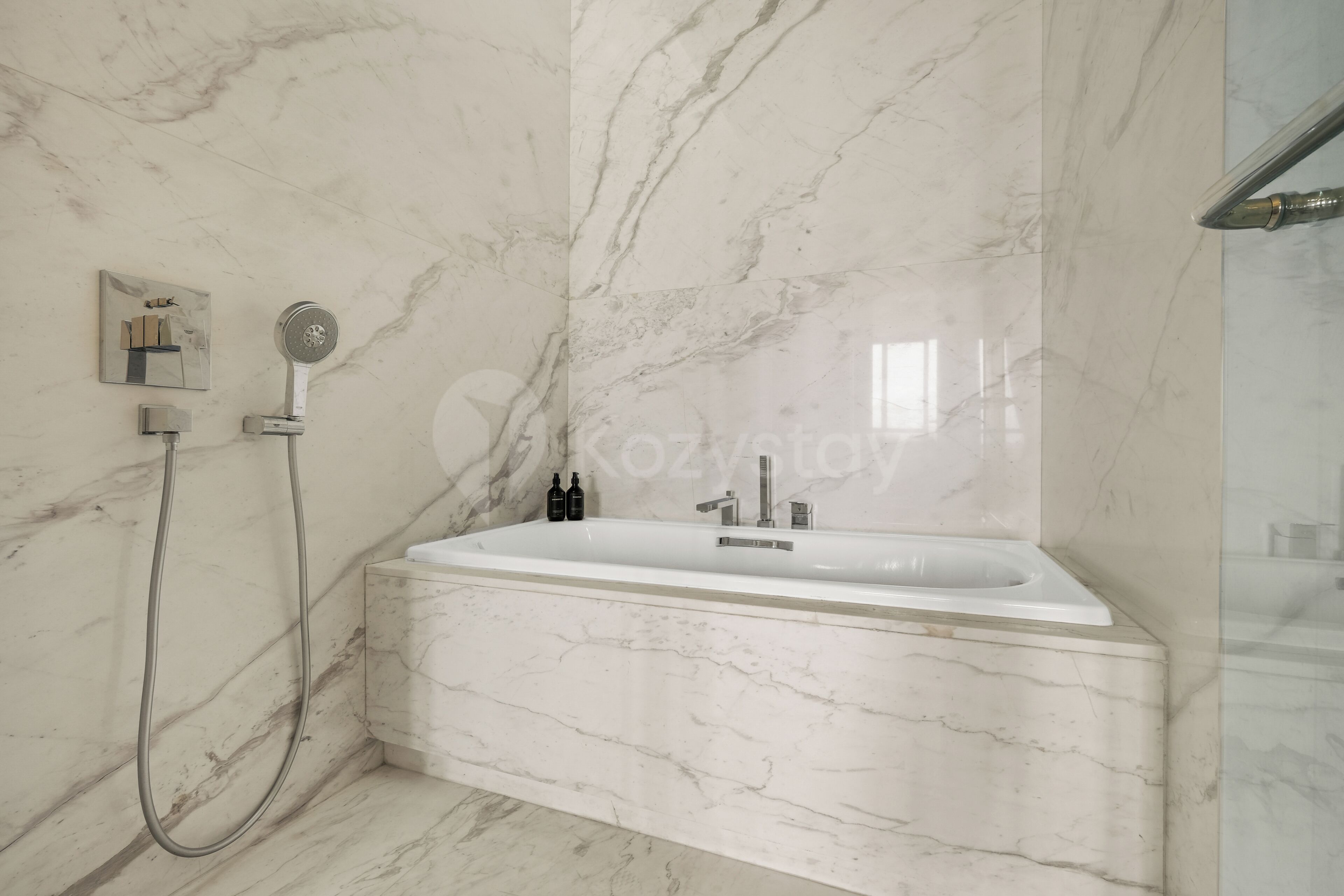 A modern bathroom with a freestanding bathtub, a handheld showerhead, and a wall-mounted faucet.