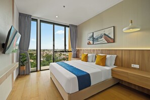 Ein modernes Hotelzimmer mit einem großen Bett, einem Fernseher, Blick auf die Stadt und einem Gemälde an der Wand.