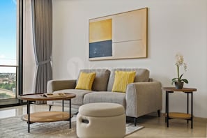 Een moderne woonkamer met een bank, twee bijzettafels, een salontafel en een potplant.