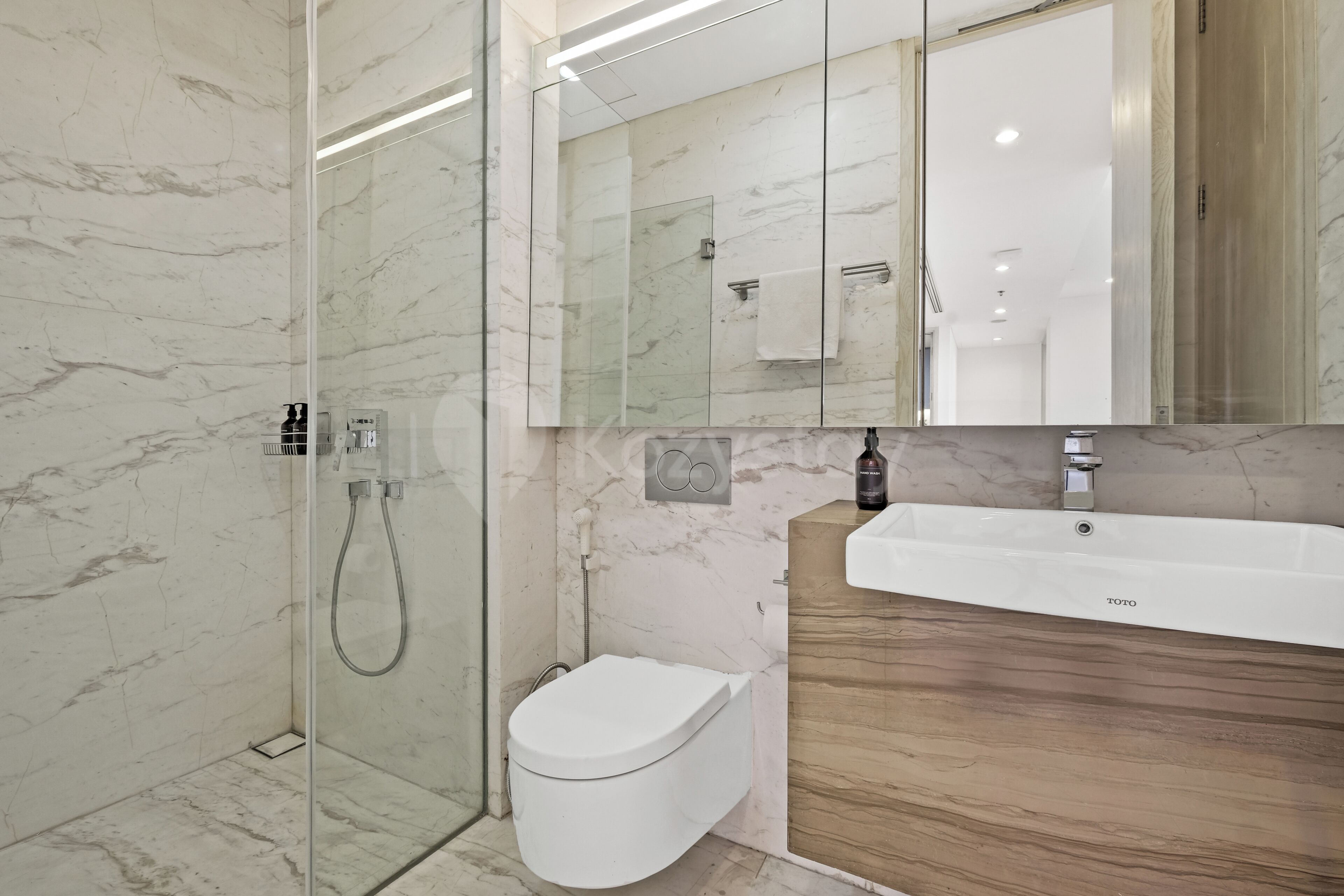 Een moderne badkamer met een douchecabine van glas, een toilet en een wastafelmeubel met een wastafel.