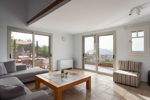 A spacious living area with a sofa, a coffee table, and a patterned armchair. - Melitta Villa Aegina, Villa (Aegina)