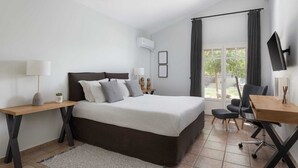 Ein modernes Schlafzimmer mit Bett, Nachttischen, einem Schreibtisch und einem Sessel.