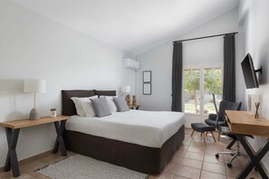 Ein modernes Schlafzimmer mit Bett, Nachttischen, einem Schreibtisch und einem Sessel.