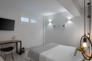 A bedroom with a bed, a desk, a chair, a TV, and wall-mounted lights. - Melitta Villa Aegina, Villa (Aegina)