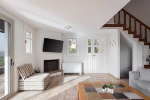 Ein Wohnzimmer mit Sofa, Fernseher, Kamin und einer Treppe.