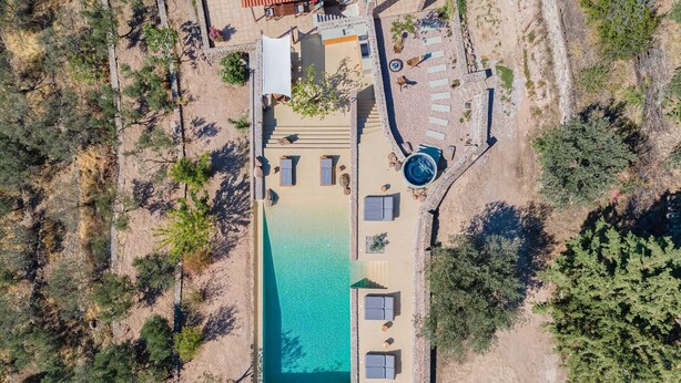 Eine Vogelperspektive auf ein Anwesen mit Swimmingpool, mehreren Sitzbereichen und einer Terrasse.