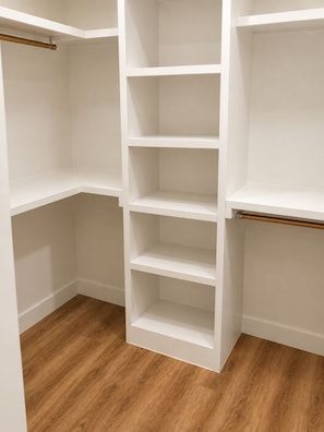 A white closet with multiple shelves and a wooden floor. -     Modern 4BR/4BA Townhome w/ Rooftop Near Downtown Dallas (Dallas)