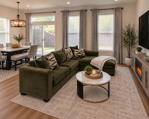 A living room with a sectional sofa, a dining table, and a fireplace. -     Modern 4BR/4BA Townhome w/ Rooftop Near Downtown Dallas (Dallas)