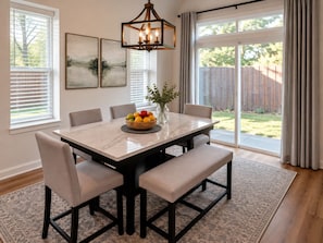 A dining area with a marble table, cushioned chairs, a fruit bowl, and a vase with greenery. -     Modern 4BR/4BA Townhome w/ Rooftop Near Downtown Dallas (Dallas)