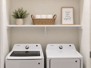 A laundry area with two Samsung washing machines, a wicker basket with towels, a potted plant, and a framed sign saying 'WASH DRY FOLD repeat'. -     Modern 4BR/4BA Townhome w/ Rooftop Near Downtown Dallas (Dallas)