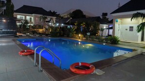 Una piscina con un salvavidas, una escalera metálica y un cartel que indica zona de natación.