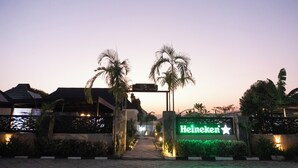 Entrada de hotel con un cartel de 'Heineken' y palmeras.