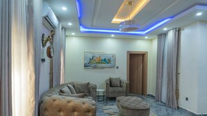 Una sala de estar moderna con un sofá, un sillón, un reposapiés y un cuadro en la pared.