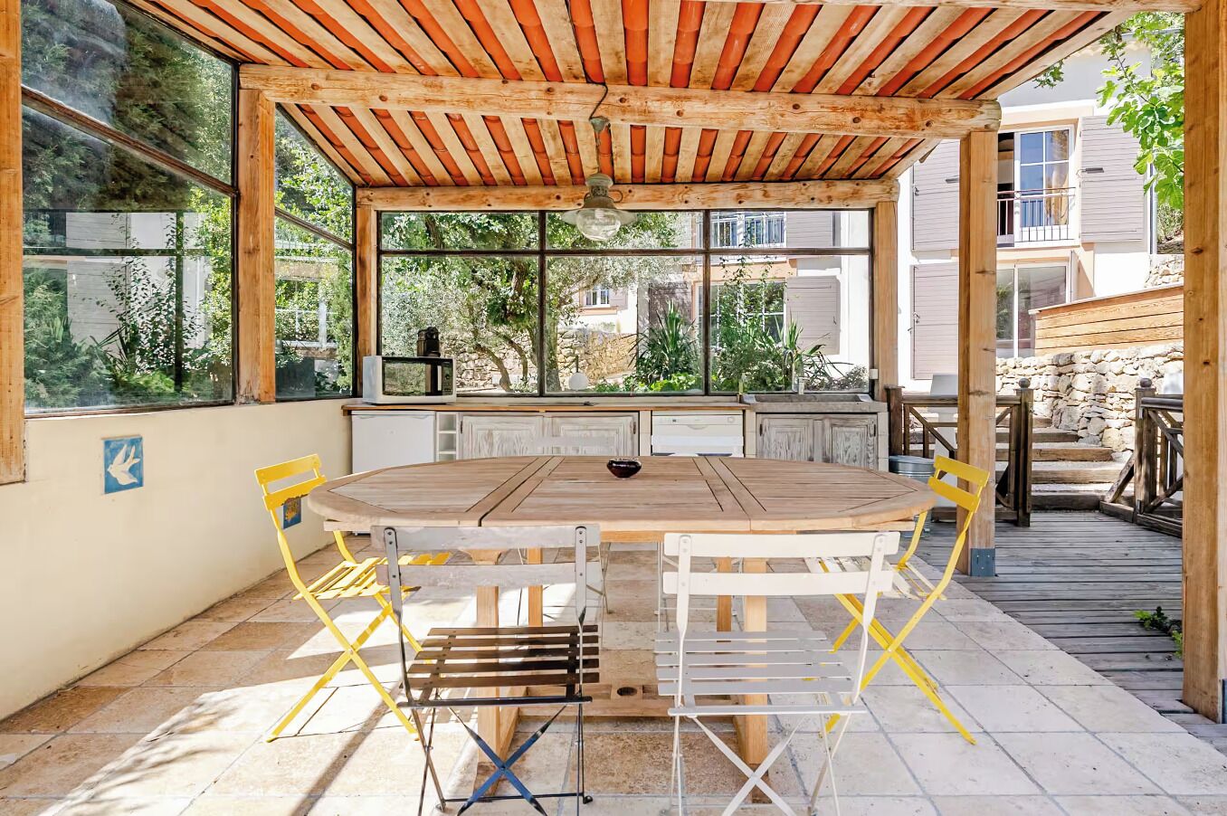 Une terrasse extérieure avec une table et des chaises en bois, une pergola au-dessus et une vue sur les environs.