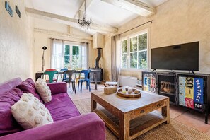 A living room with a purple sofa, wooden coffee table, and a television on a black stand. - Provençal villa surrounded by nature • Swimming Pool & Hot Tub (Aubagne)