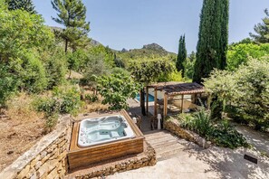 A hot tub surrounded by a wooden deck, a pergola, and lush greenery. - Provençal villa surrounded by nature • Swimming Pool & Hot Tub (Aubagne)