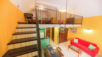 Ein mehrstöckiger Wohnraum mit Treppe, einem Essbereich, einem roten Sofa und einer Küchenzeile.