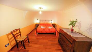 Ein Schlafzimmer mit einem Bett, einem Holzschrank, einem Stuhl und einem kleinen Tisch mit einer Pflanze.