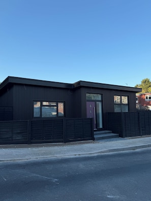 A modern building with a flat roof, large windows, and a dark facade.
