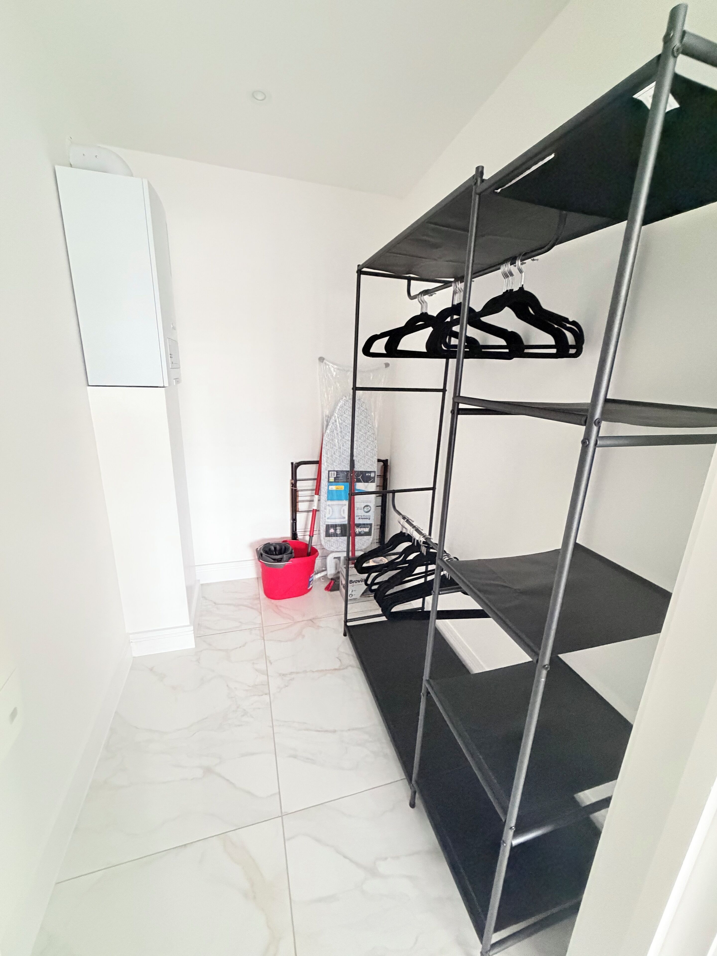 Habitación pequeña y limpia con una cama litera, un trapeador, un cubo y un aire acondicionado de pared.