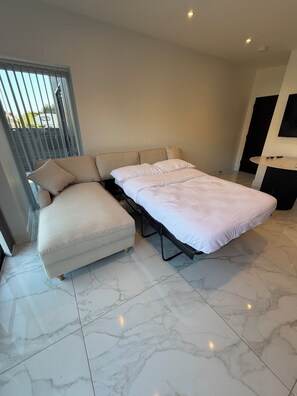 A modern bedroom with a bed, a sofa, and a small table.