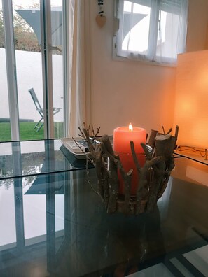 A glass table with a candle in a branch-shaped holder, a keyboard, and a window with a view of a lawn and chairs. - Le Patio de Bouzigues: Free parking, 3 minutes from downtown and the beach (Bouzigues)