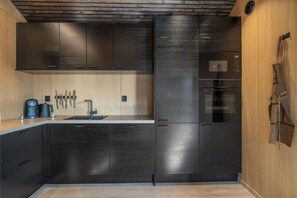 Eine moderne Küche mit dunklen Schränken, einem eingebauten Backofen und einer Kaffeemaschine.