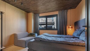 Een slaapkamer met een bed, een bank, een raam en een lamp.