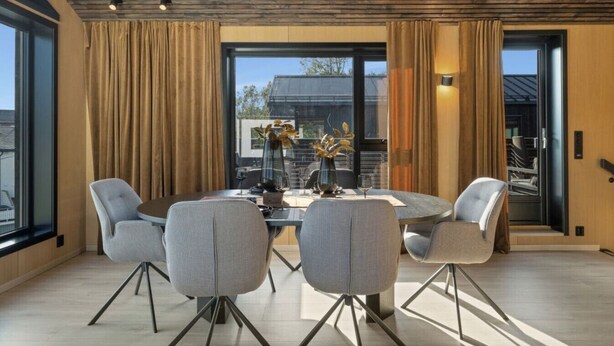 Een moderne eetruimte met een ronde tafel, vier stoelen en een vaas met bloemen.