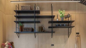 Een moderne keuken met houten kastjes, zwarte metalen planken en een inbouwfornuis.
